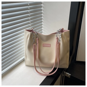 Detail of off-white tote bag with pink straps and fashion label by white window blinds