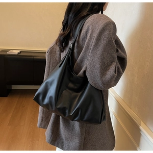Detailed side view of a large black leather hobo bag with silver adjustable buckle strap