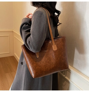 Close-up of brown vintage leather tote bag with gold lettering shown on person