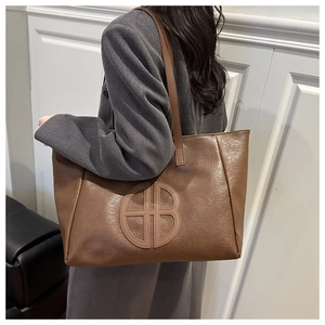 Close-up of brown oversized tote bag with retro PU leather texture and embossed logo