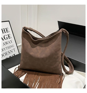 Détail d'un sac à bandoulière en daim marron foncé avec de longues franges bohèmes