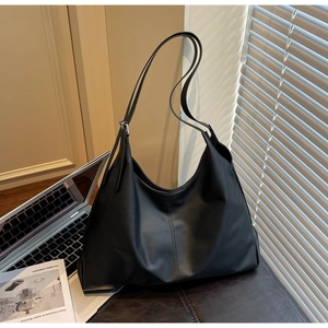 Detail of black leather hobo tote bag featuring vertical stitching and adjustable buckle