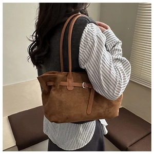 Detailed view of brown faux suede tote bag with stylish buckle strap and long shoulder handles