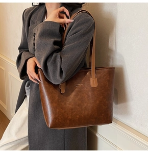 Detail view of large brown vintage tote bag with elegant texture and slim straps