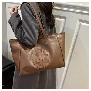 Close-up of vintage brown tote bag with wrinkled texture and embroidered circular logo