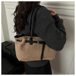 Detailed back view of model wearing a brown suede tote bag with black leather shoulder straps