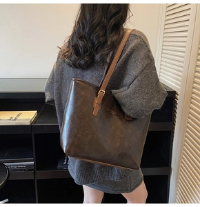 Detail of vintage coffee brown leather tote bag with gold logo and adjustable strap