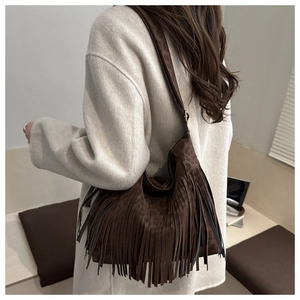 Detail of a dark brown suede hobo bag featuring long tassels for a trendy boho style