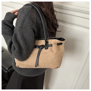 Detail view of khaki faux suede tote bag with contrast black handles on a female model