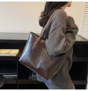 Detail of retro brown leather tote bag with gold lettering and adjustable metal buckle strap