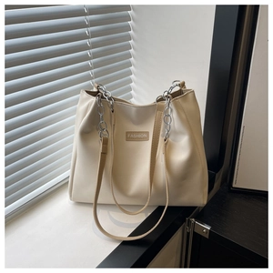 Detail of cream tote bag featuring silver chain strap and fashion logo on leather