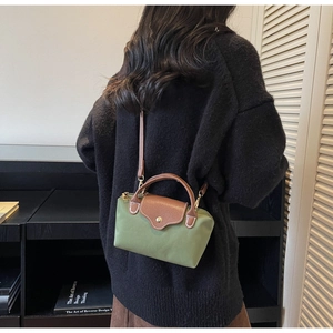 Green canvas and brown leather mini crossbody bag shown on model with black sweater