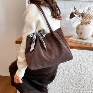 Brown suede tote bag with pleated silk scarf detail shown in a stylish lifestyle setting