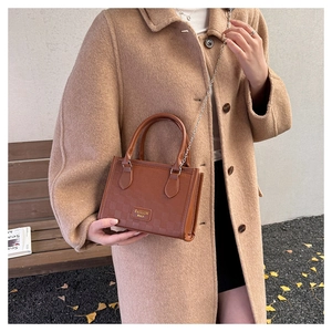 Détail du sac bandoulière marron vintage avec gaufrage à damier et garniture dorée