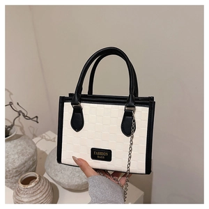 Détail d'un sac à bandoulière damier noir et blanc avec une fine chaîne en métal
