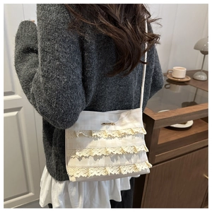 Detail view of cream lace crossbody bag with plaid texture and delicate frill layers
