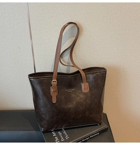 Detail of dark brown vintage tote bag with contrast tan handles on a book background