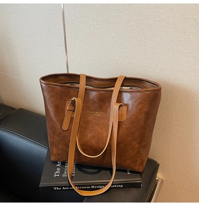 Detail of vintage brown tote bag texture with adjustable handle and golden logo print