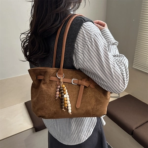 Brown faux suede hobo bag for women with vintage tassel and buckle detail shown on model