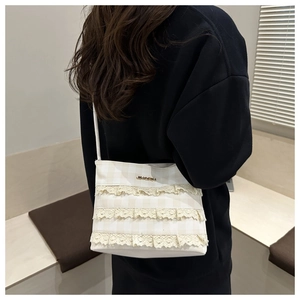 Detailed back view of a beige lace shoulder bag featuring tiered ruffles and metallic logo