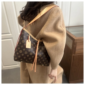 Close-up of brown monogram tote bag featuring leather shoulder straps and side drawstrings