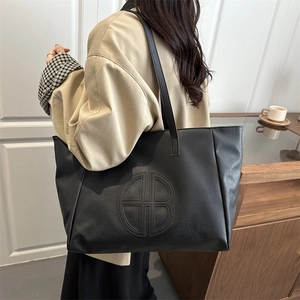 Minimalist black large capacity tote bag with embossed circular logo for daily commute