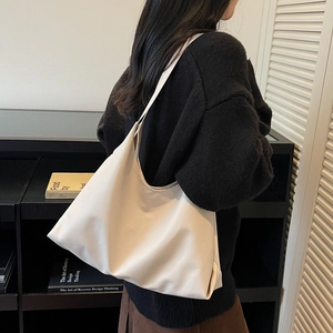 Minimalist large off-white tote bag in soft leather shown on shoulder with side view