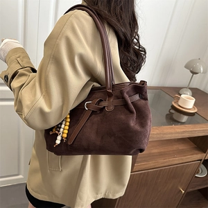 Vintage dark brown suede tote bag with retro beaded charm in a warm indoor setting