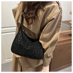 Detail of black leopard print hobo bag worn with a khaki trench coat for commute style