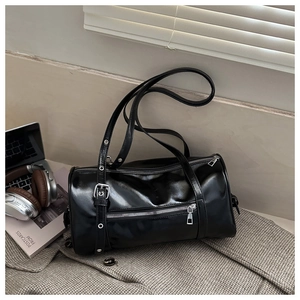 Close-up of black glossy leather boston bag on wool coat with laptop and headphones