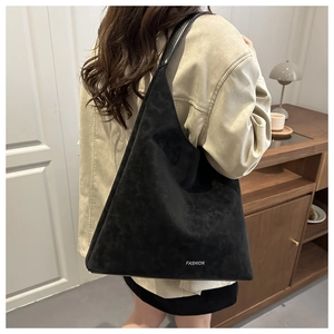 Dettaglio di una borsa hobo nera con texture in pelle scamosciata opaca e scritta fashion