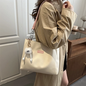Minimalist beige tote bag with pink leather straps and a cute plush monster keychain