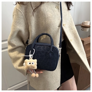 Detail of navy blue suede handbag with leopard pattern and plush cookie charm accessory
