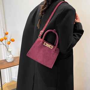Chic burgundy suede rectangular shoulder bag with golden lock shown on a model