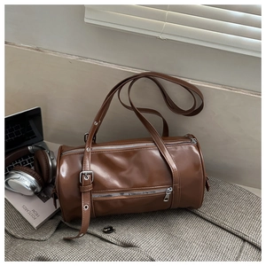 Detailed view of a brown vintage cylinder bag with double zippers on a gray suit jacket