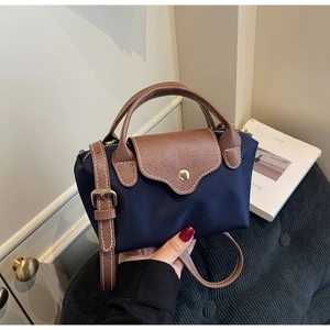Detail of dark blue nylon mini bag with brown leather flap and adjustable strap
