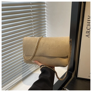 Dettaglio borsa a tracolla beige scamosciata con catena dorata spessa e patta alla moda