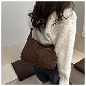 Close-up of leopard print hobo bag in brown suede fabric worn on shoulder for retro style