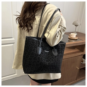 Rear view of a model wearing a large leopard print tote bag with black shoulder straps