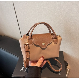 Detail of light brown nylon handbag with dark leather flap and adjustable strap