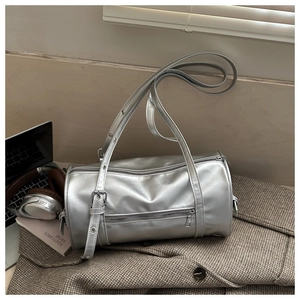 Detailed close-up of a silver cylindrical shoulder bag on a stylish brown checkered blazer