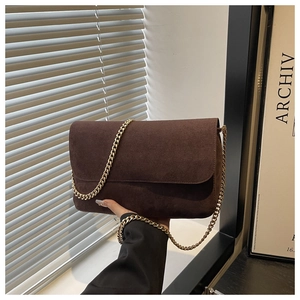Dettaglio borsa in pelle scamosciata marrone scuro con catena dorata e patta classica