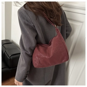 Dettaglio della borsa hobo bordeaux con trama leopardata sulla spalla della modella