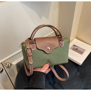 Detail of army green nylon crossbody bag with brown leather handles and flap closure