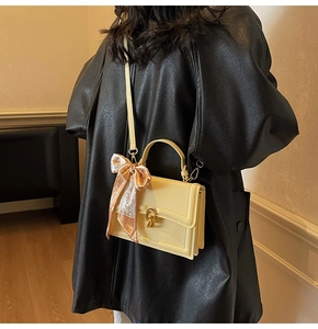 Dettaglio borsa a tracolla in pelle crema con chiusura dorata e foulard in seta