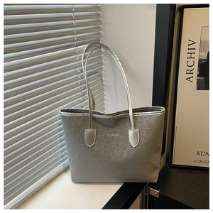 Detail showing high-gloss silver-grey tote bag with subtle leopard print and FASHION logo