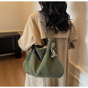 Détail du sac cabas en velours côtelé vert foncé avec une bandoulière rayée stylée