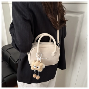 Detail of a beige square crossbody bag featuring a cute brown plush star charm on the side