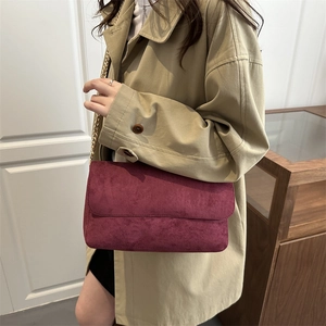 Elegante borsa a tracolla in pelle scamosciata bordeaux con catena d'oro su trench
