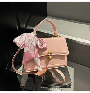 Dettaglio borsa in pelle rosa con chiusura a scatto dorata e manico con foulard a fiori